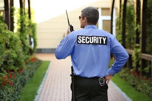 Uniformed unarmed security officer on radio patrolling a residential community walkway